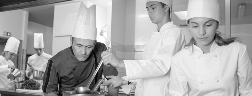 Bild von jungen Menschen in der Ausbildung in einer Küche mit Küchenchef. Bild von jungen Menschen in der Ausbildung in einer Küche mit Küchenchef.