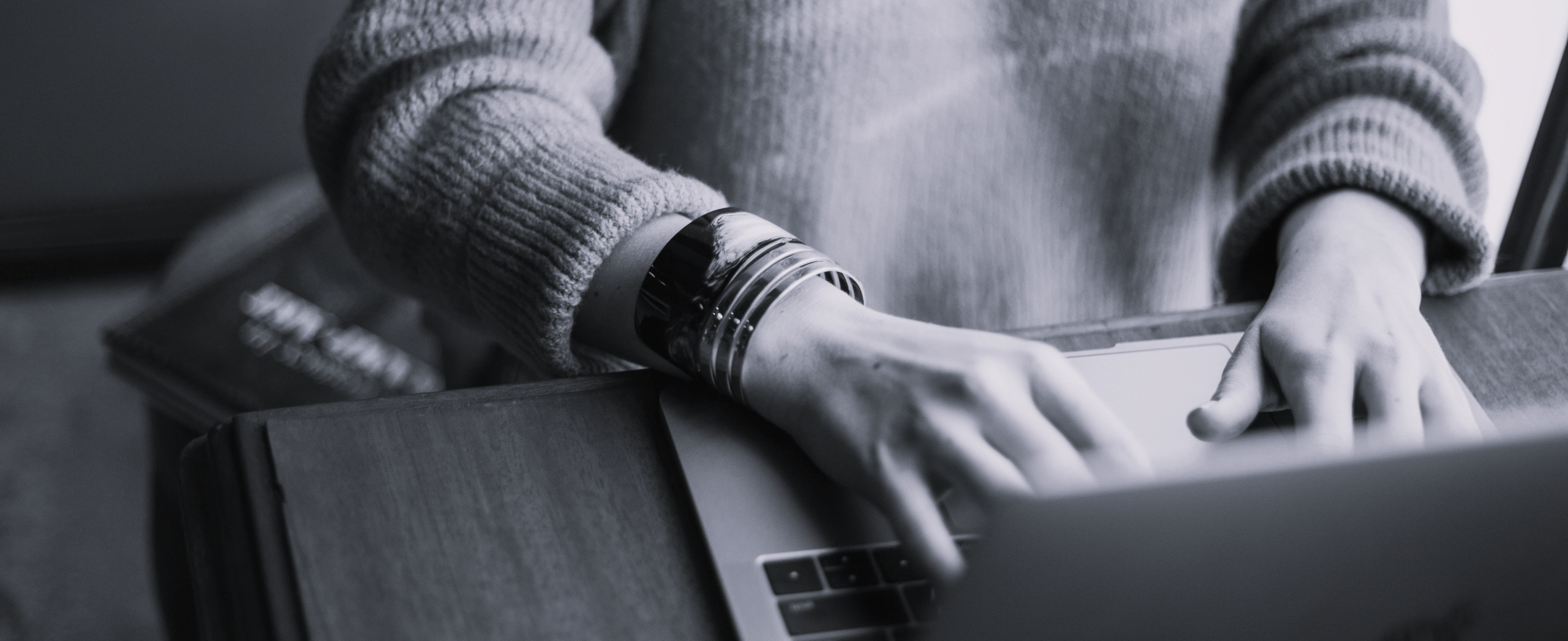 Person am Schreibtisch sitzend, vor sich einen Laptop